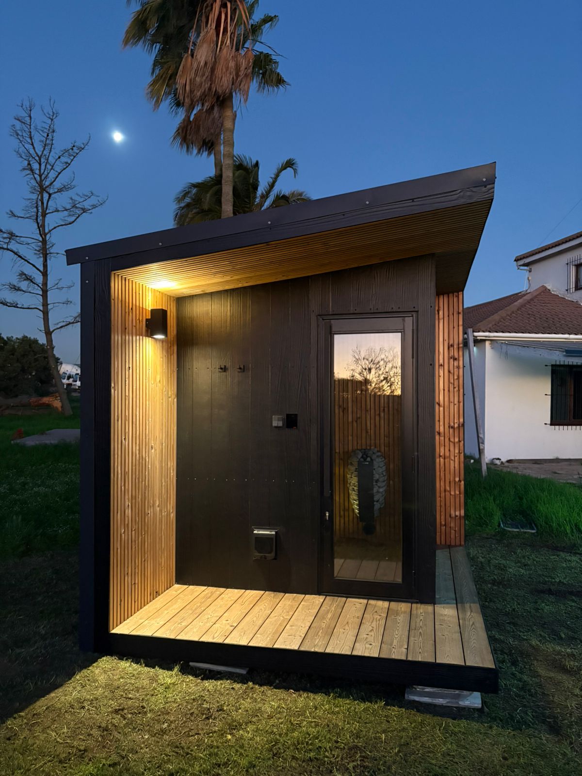 Khaya sauna at night in a residential backyard